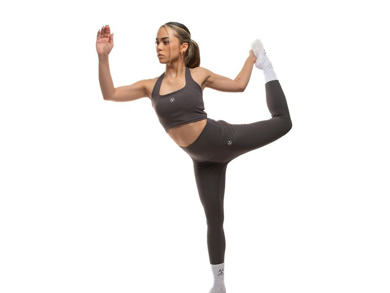 Woman in a dynamic but controlled stretching pose in a bright studio.